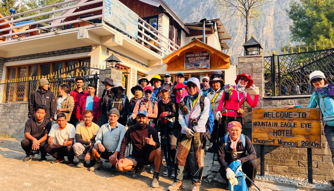 Trekking group posing in front of Mountain Eagle Eye Hotel in Chame, Manang District, during the Annapurna Circuit Trek in Nepal.